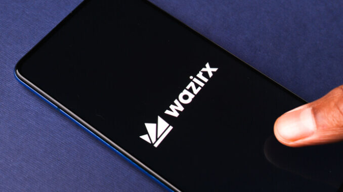 WazirX (WRX) token dumps after Binance delisting news The WazirX logo on a phone